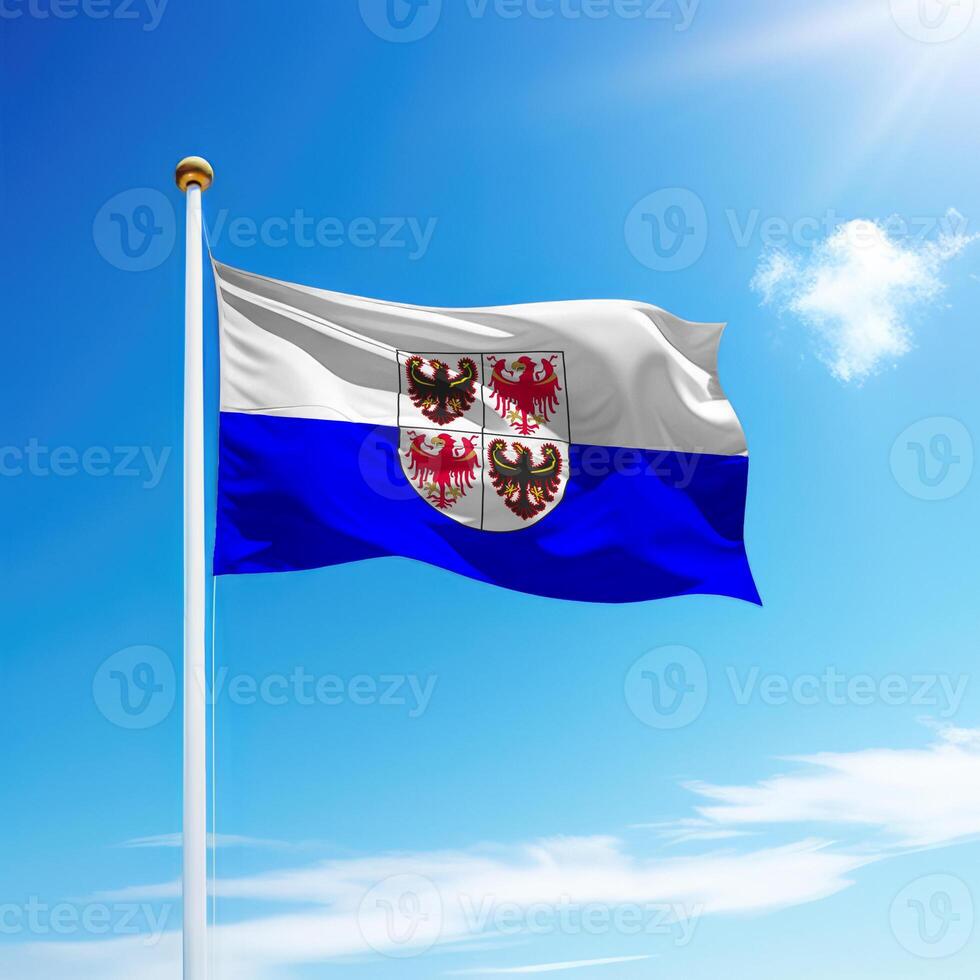Waving flag of Trentino-South Tyrol is a region of Italy on flagpole photo