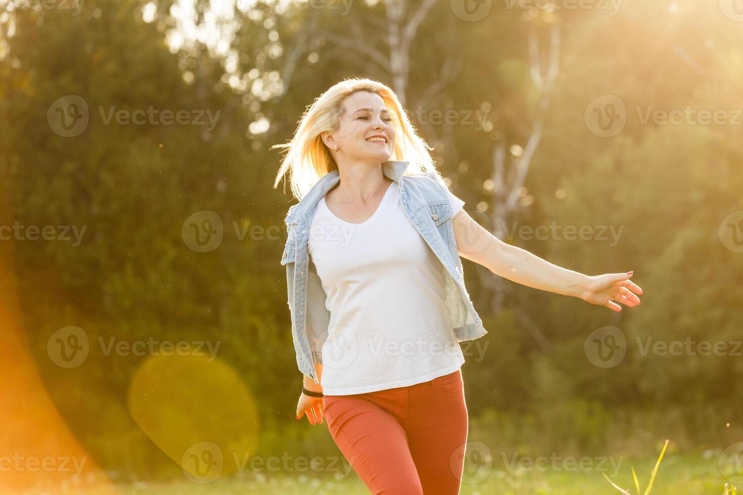 Attractive young woman enjoying her time outside in park with sunset in background. photo