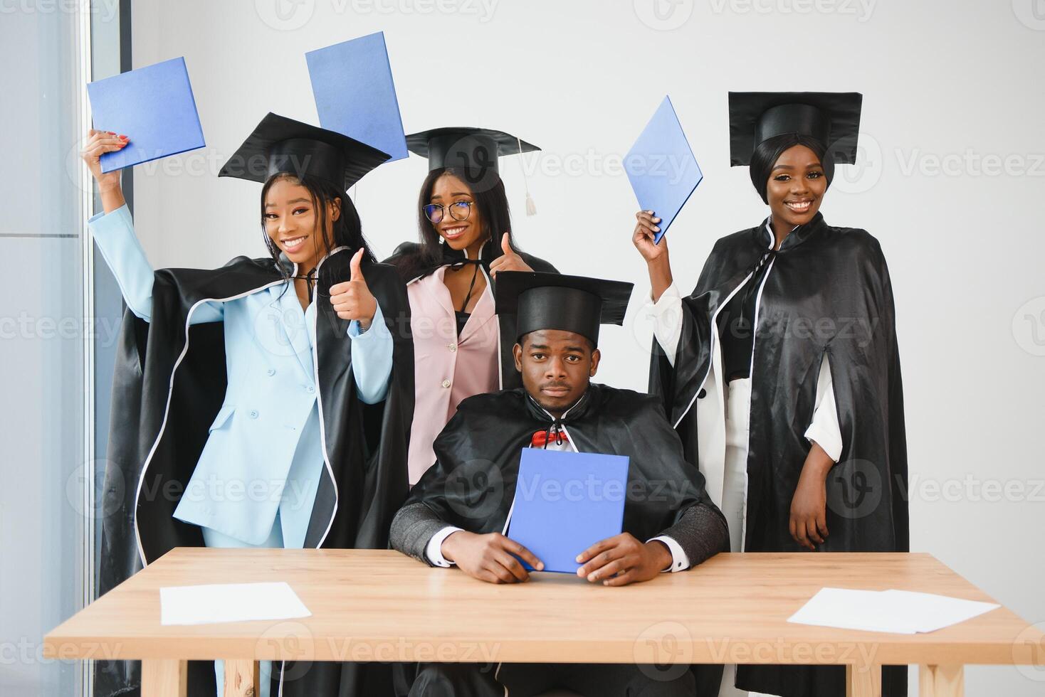 education, graduation and people concept - group of happy international graduate students in mortar boards and bachelor gowns with diplomas photo