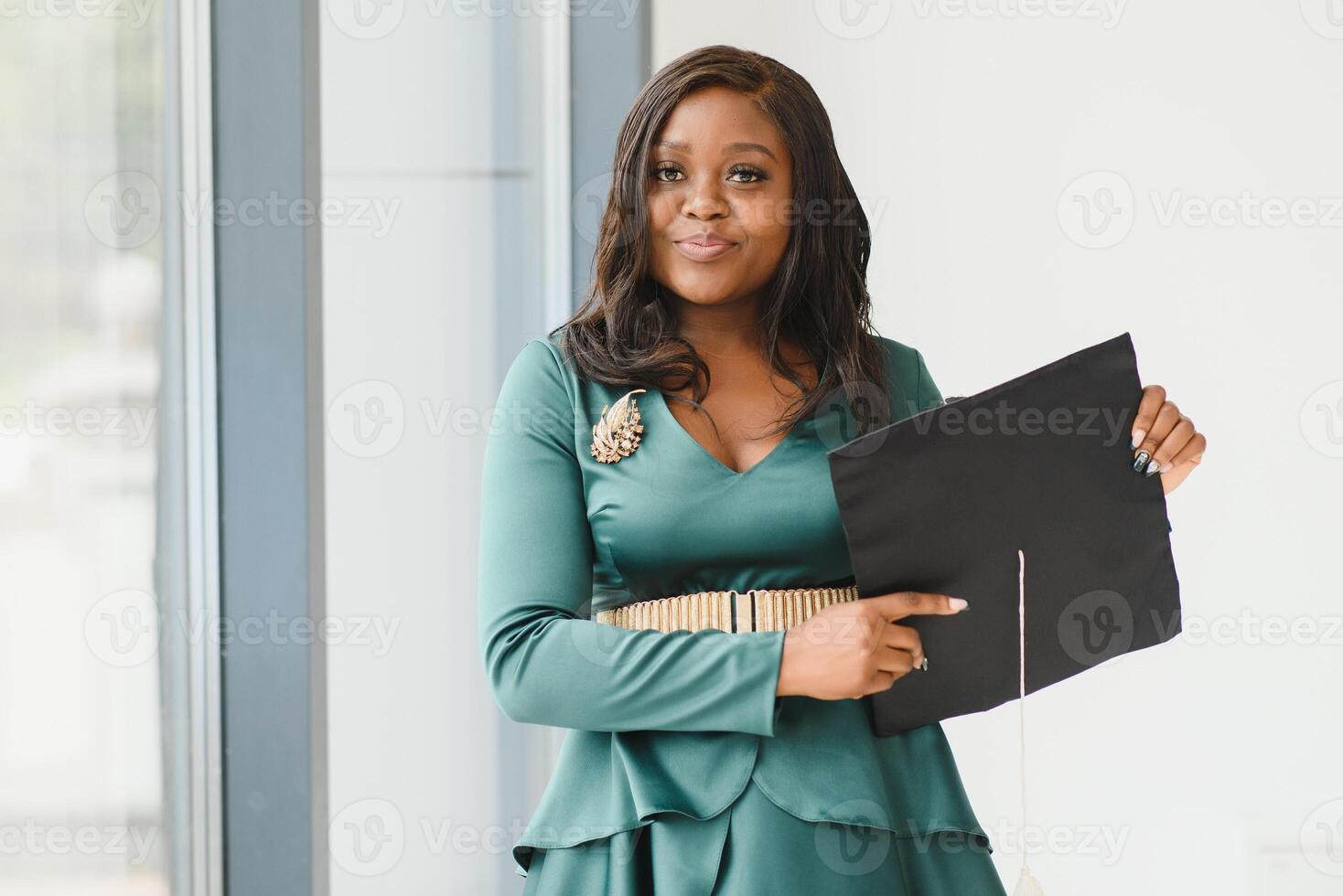 Happy Indian university student in graduation gown and cap holding diploma certificate. Portrait of mixed race Asian Indian and African. photo