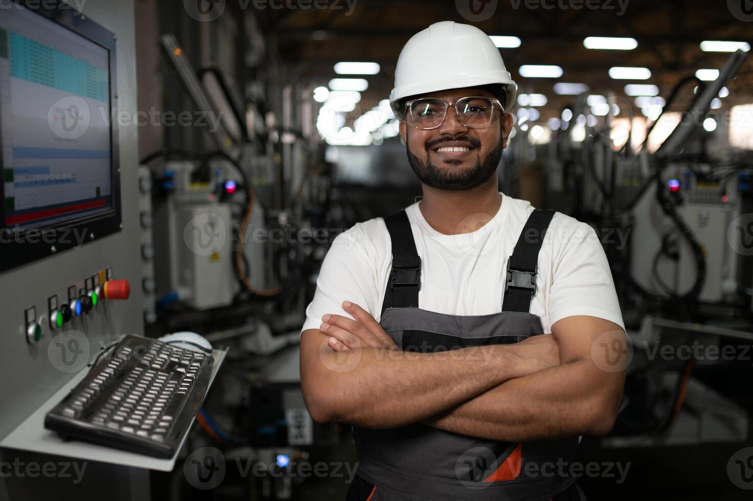 Young Indian male engineer wearing safety workwear standing in the factory photo
