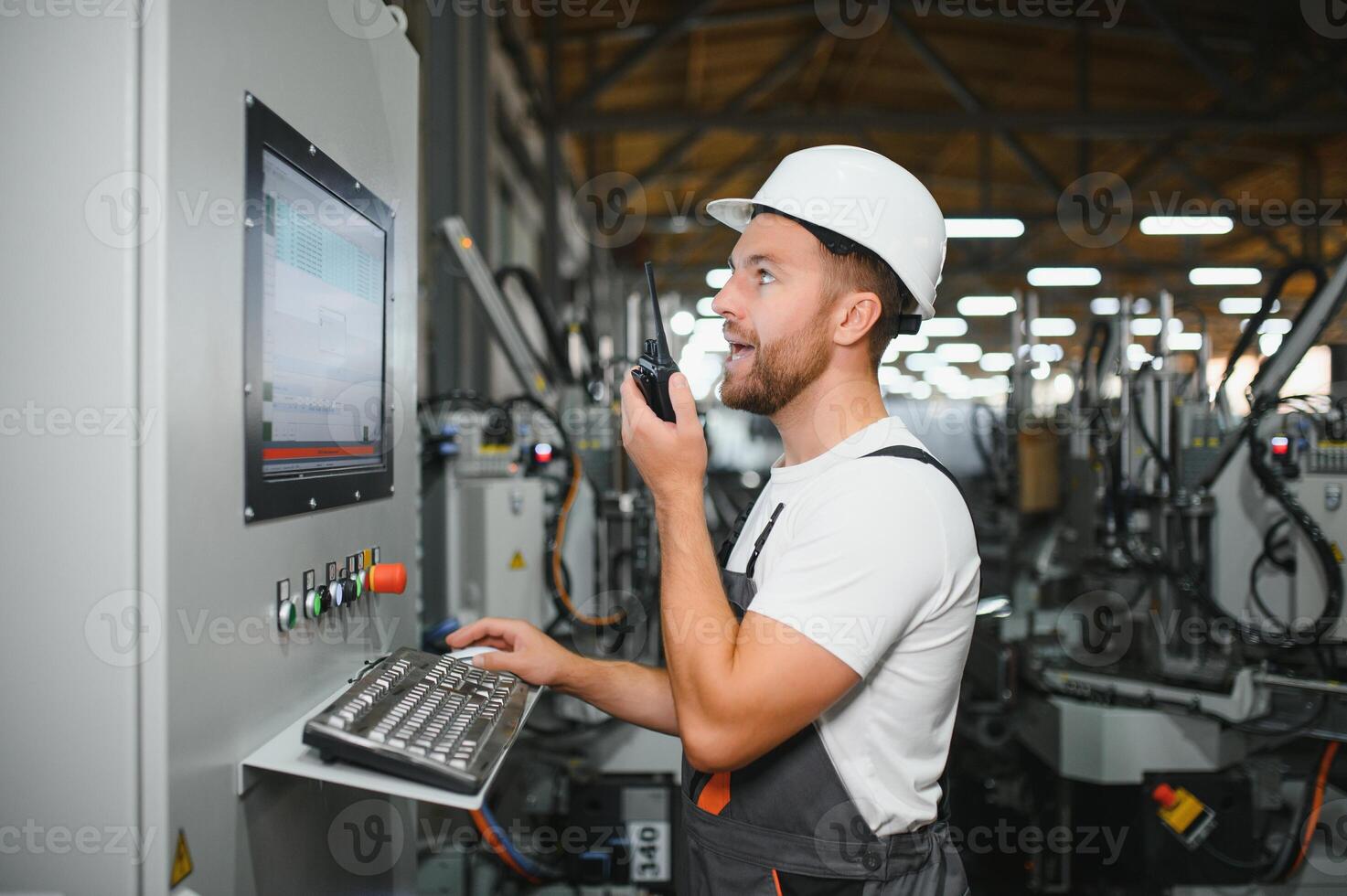 Factory male bearded worker is programming a CNC milling machine with copy space photo