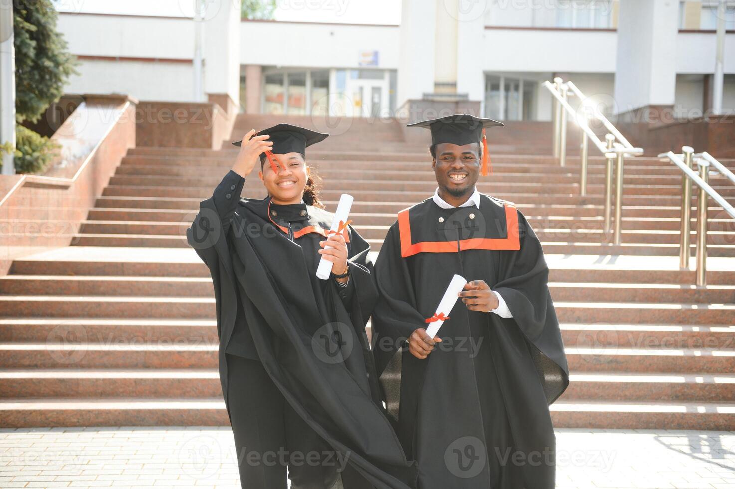 Young african man and woman graduating college, wearing a graduation gown cap photo