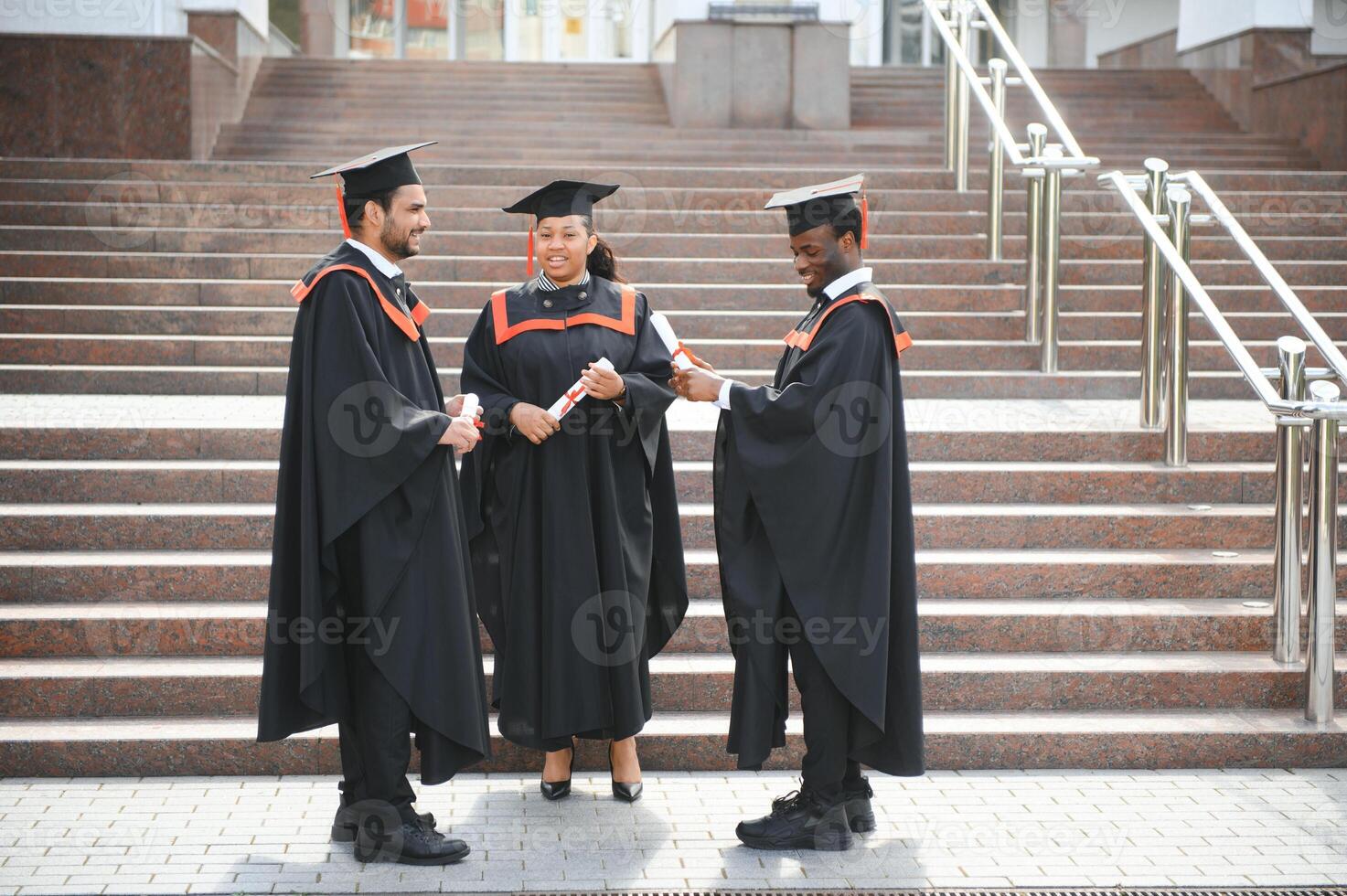 Group of multiracial graduate students with diplomas on university background photo