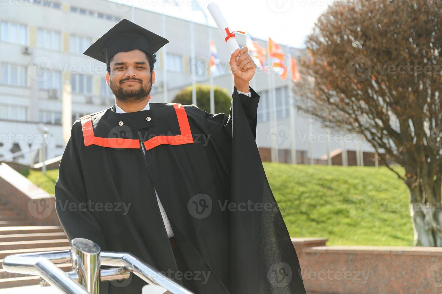 Handsome indian graduate in graduation glow with diploma photo