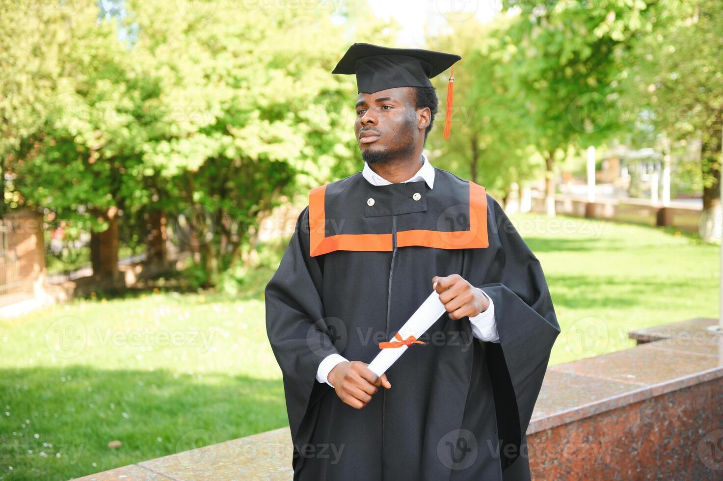 I have finally graduated. Happy young African man in graduation gowns holding diploma photo