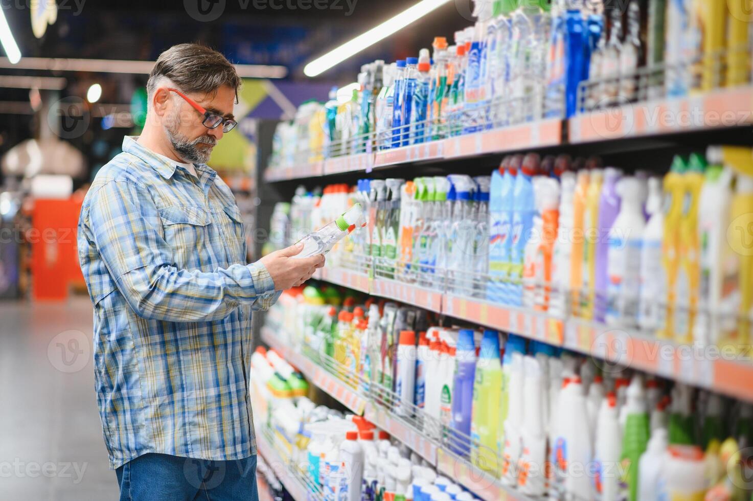Man in the supermarket in the household chemicals department. Large selection of products photo