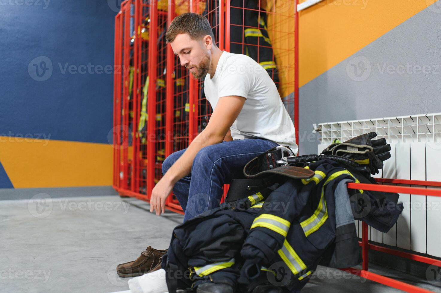 Fireman changing clothes and fastening his helmet in fire department photo