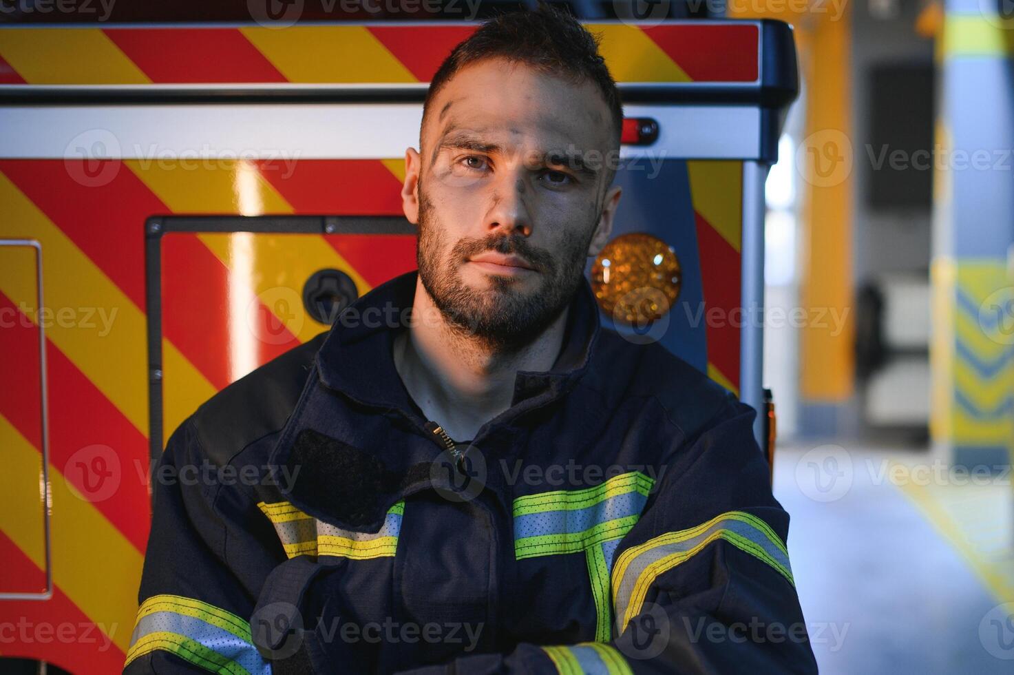 Portrait of a firefighter in a protective suit and a protective helmet standing by a fire engine after working on a fire. Close-up image photo