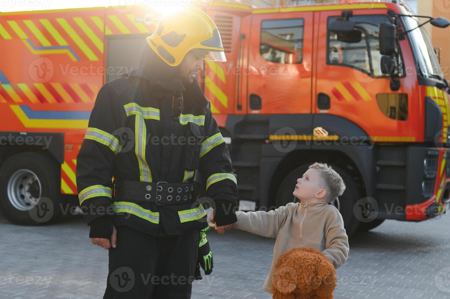 Portrait of a fireman and a little boy with a teddy bear. photo