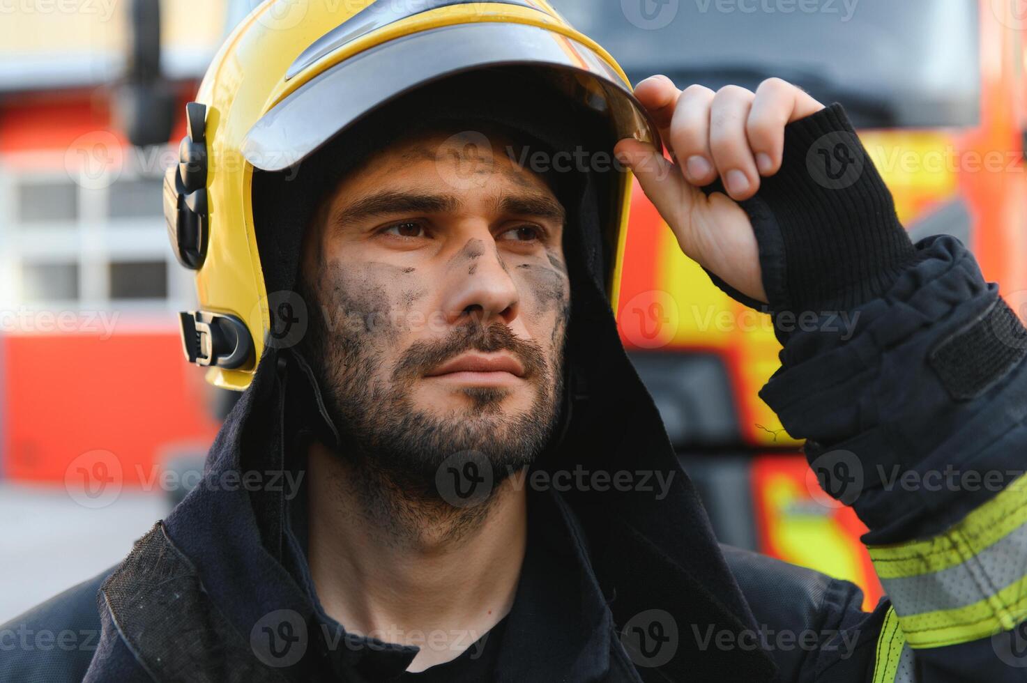 Portrait of a firefighter in a protective suit and a protective helmet standing by a fire engine after working on a fire. Close-up image photo