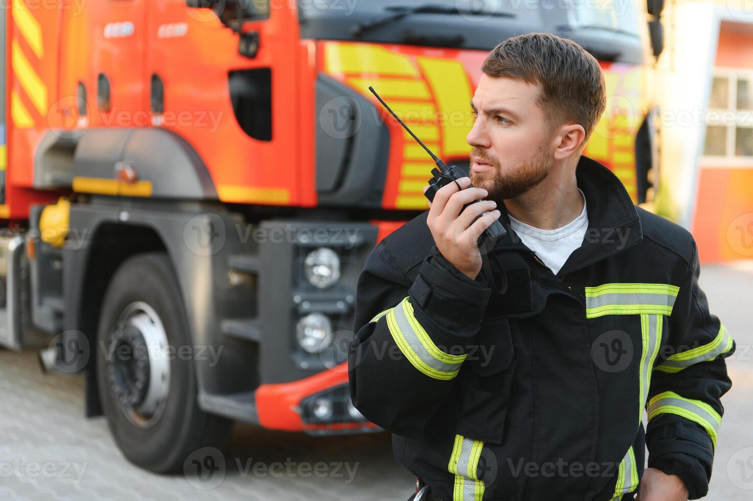 Firefighters man in a protective suit near fire truck. Protection, rescue from danger. Fire station photo