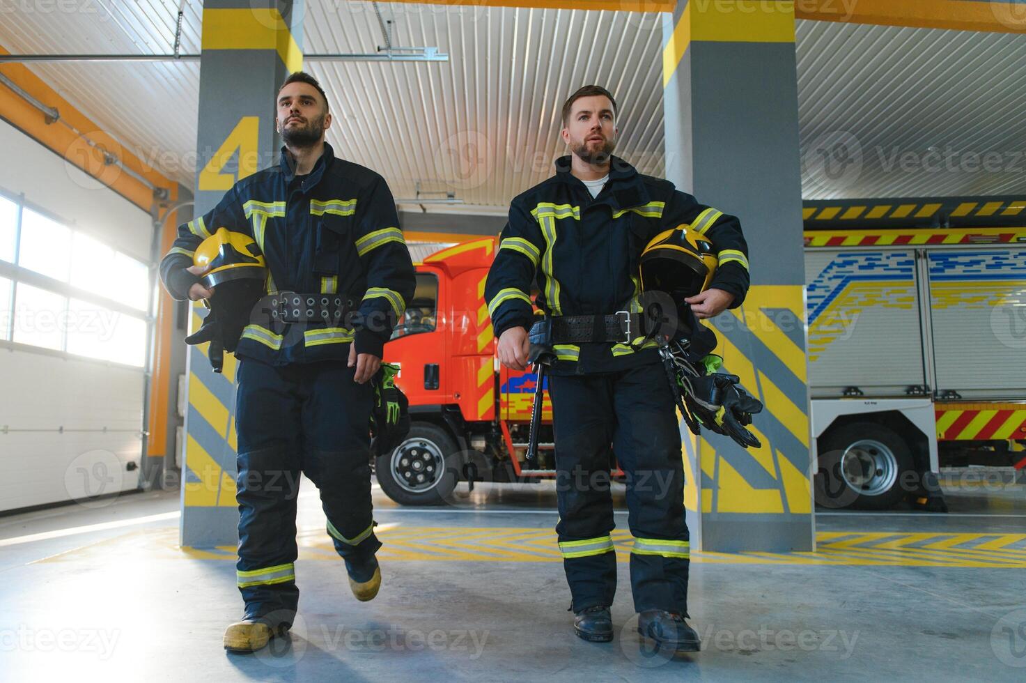 Group of firefighters at the emergency vehicle in the fire station photo