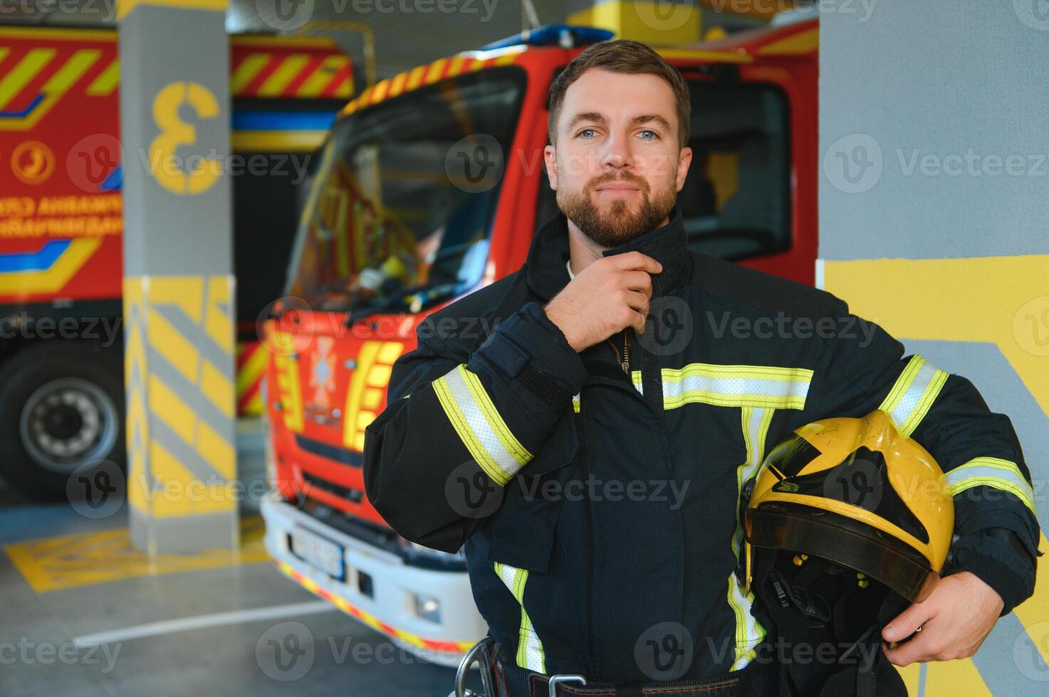 fireman in protective uniform standing near fire engine on station photo