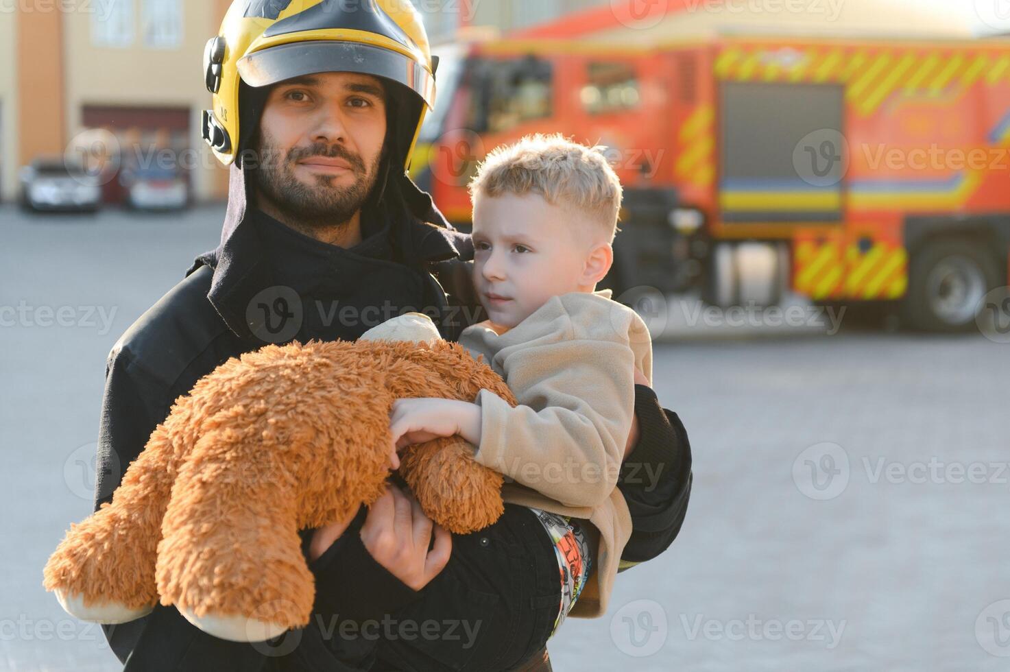 Portrait of a fireman and a little boy with a teddy bear. photo