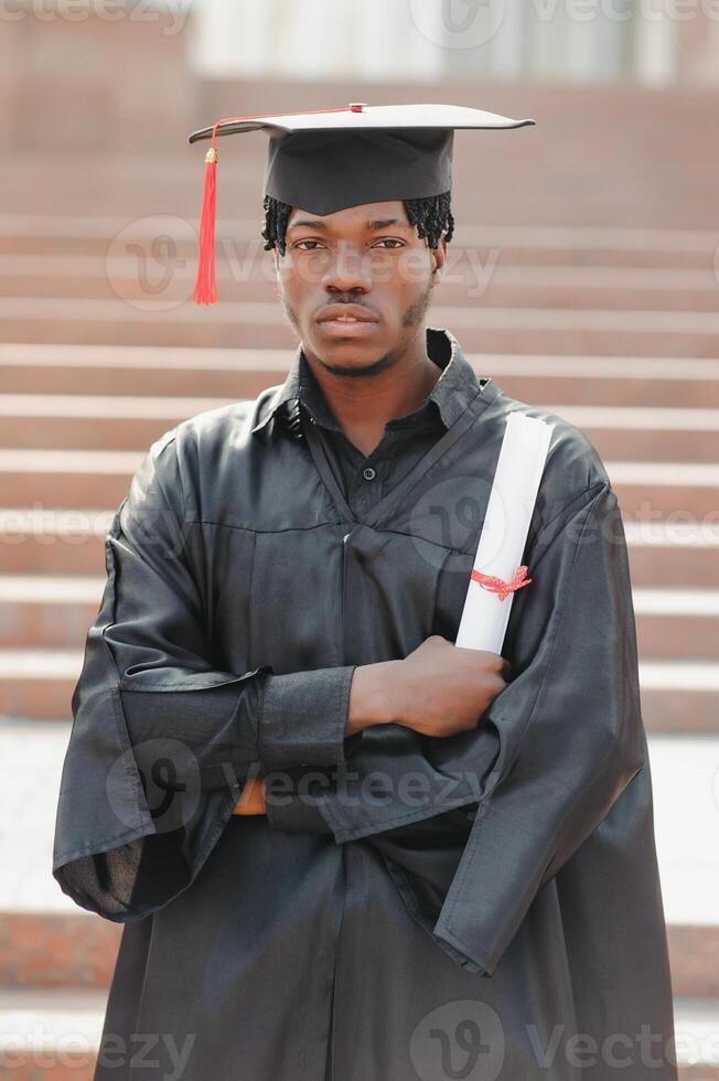 young african male graduate standing in front of university building photo