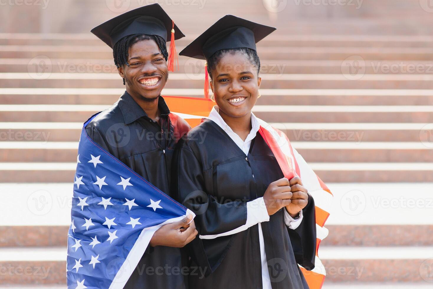 education, graduation and people concept - happy international students in mortar boards and bachelor gowns with american flag photo