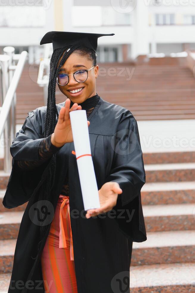 happy african american female student with diploma at graduation photo