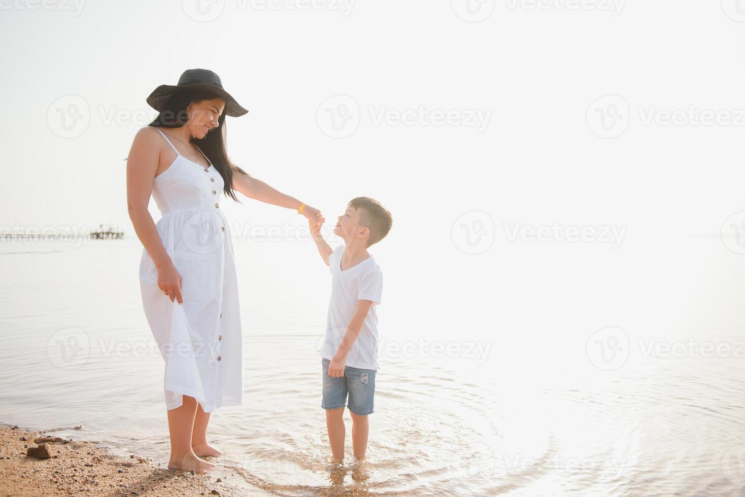mother and son walking on sunset beach photo
