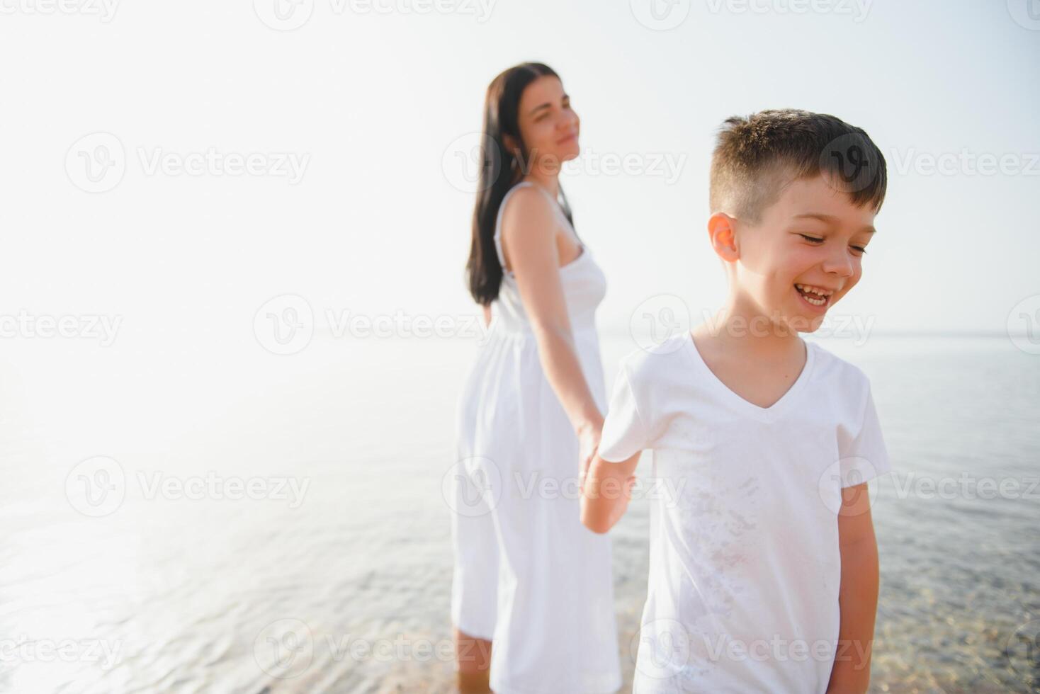 Happy mother and son walk along the ocean beach having great family time on vacation on Pandawa Beach, Bali. Paradise, travel, vacation concept photo