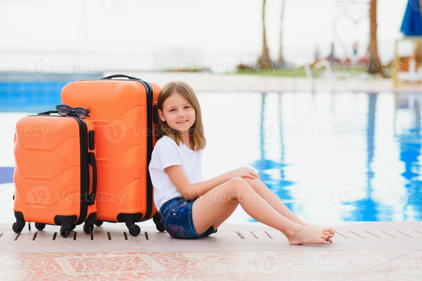 Girl with suitcases by the pool in a luxury hotel. sea and reflection, traveling and relaxing time concept. photo