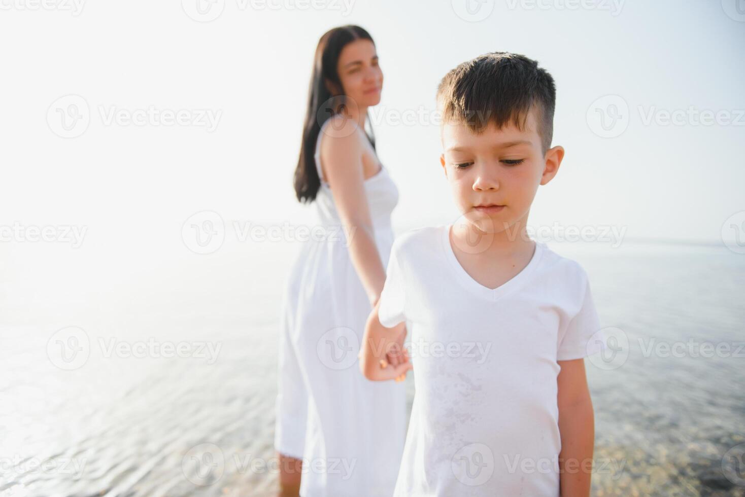 Mother and son playing on the beach at the day time. Concept of friendly family. photo
