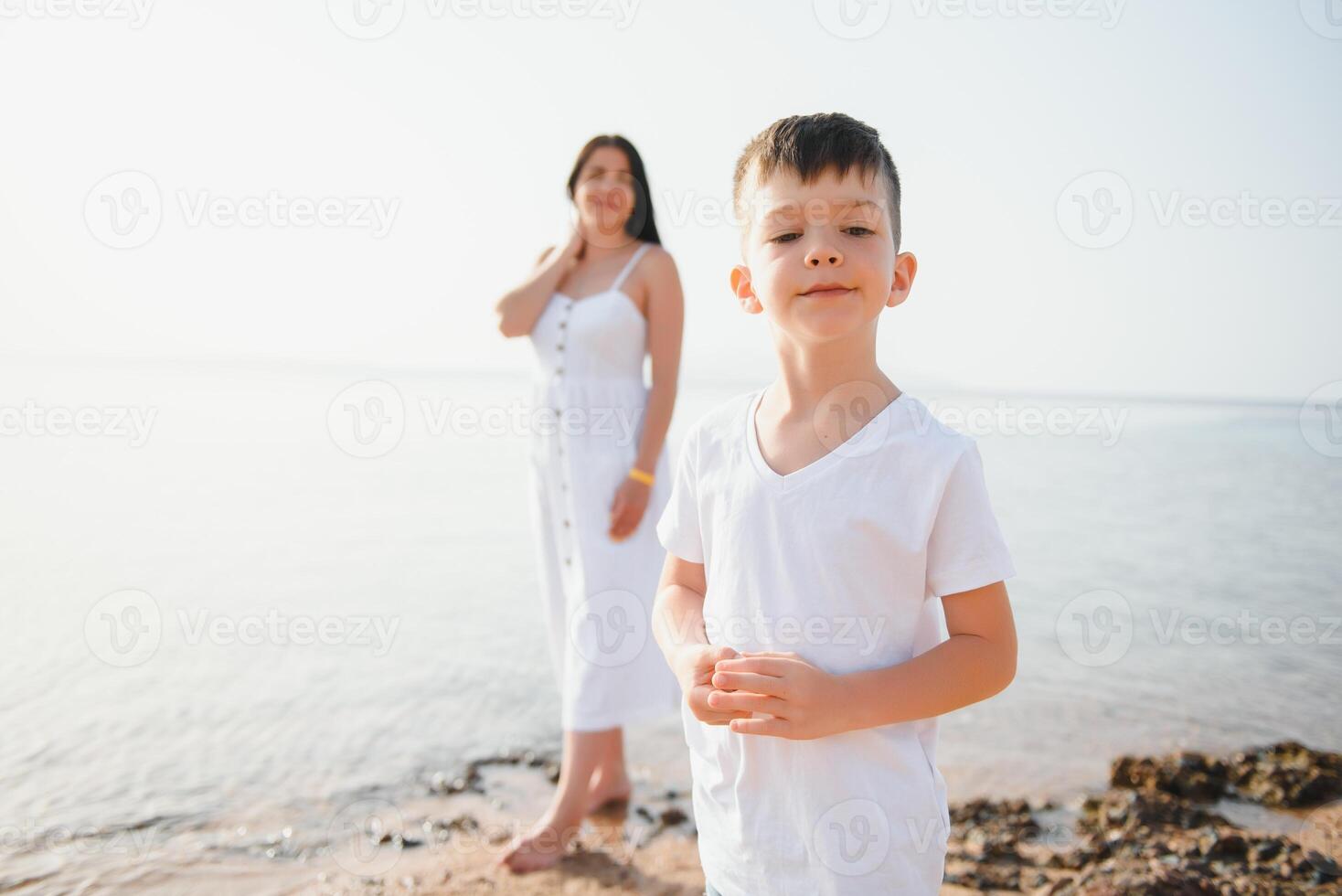 Happy mother and son walk along the ocean beach having great family time on vacation on Pandawa Beach, Bali. Paradise, travel, vacation concept photo
