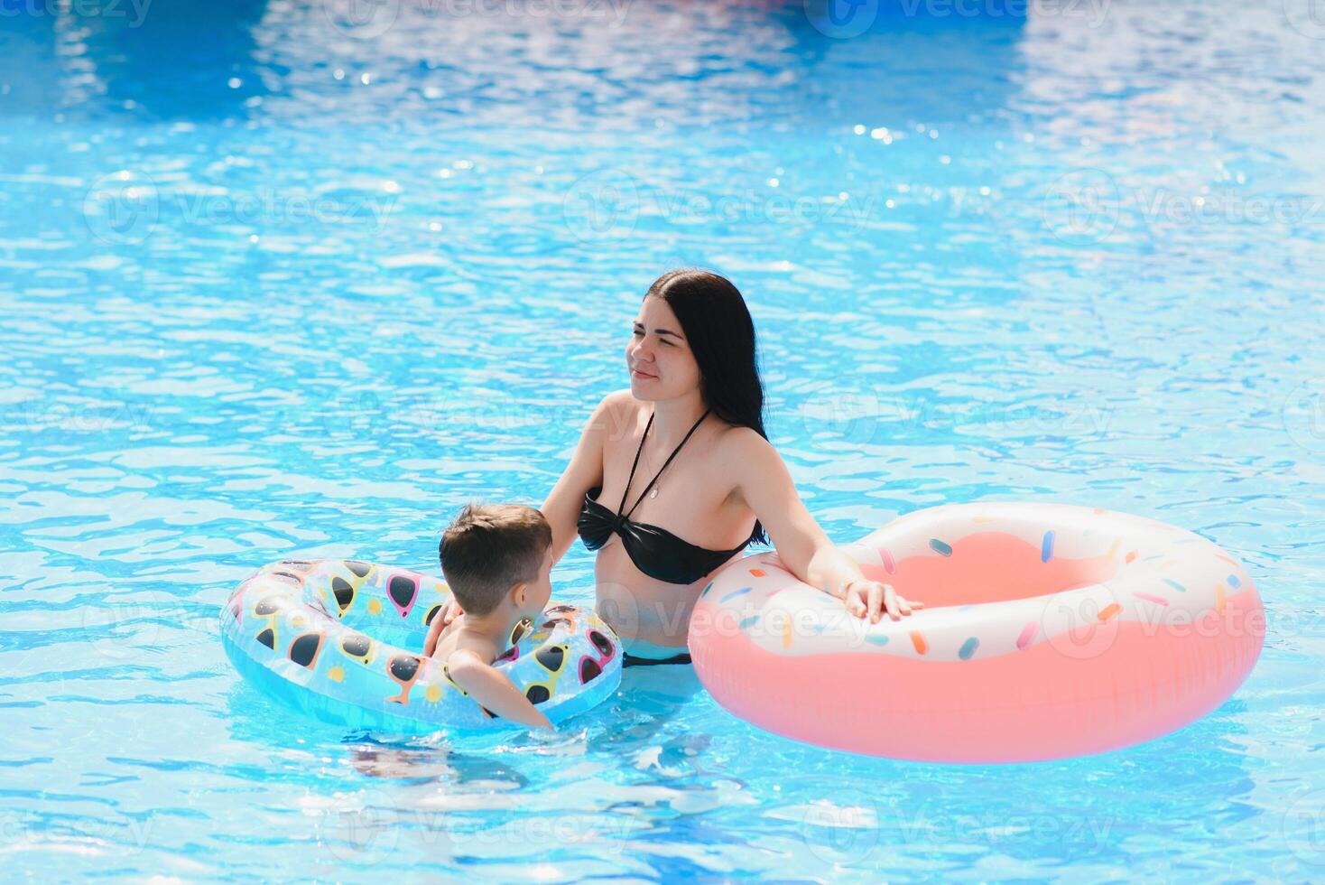 Happy child and woman playing in swimming pool. Summer vacation concept photo
