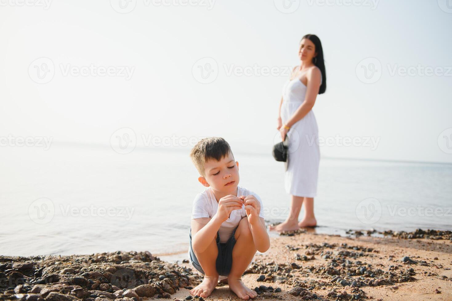 Mother and son playing on the beach at the day time. Concept of friendly family. photo