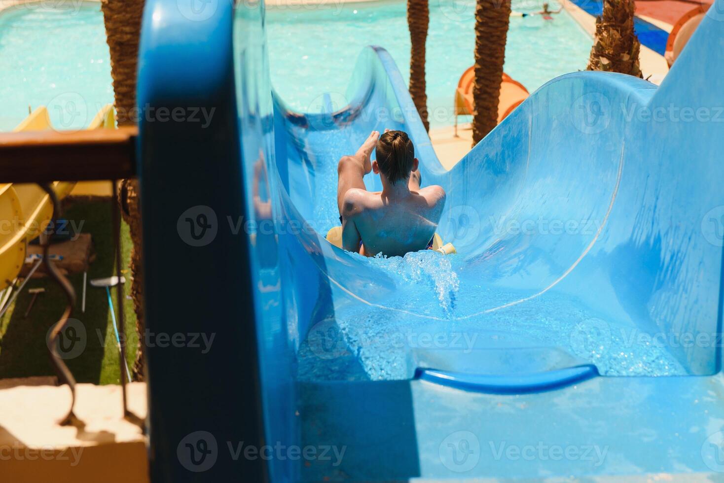 little boy sliding on the swimming pool photo