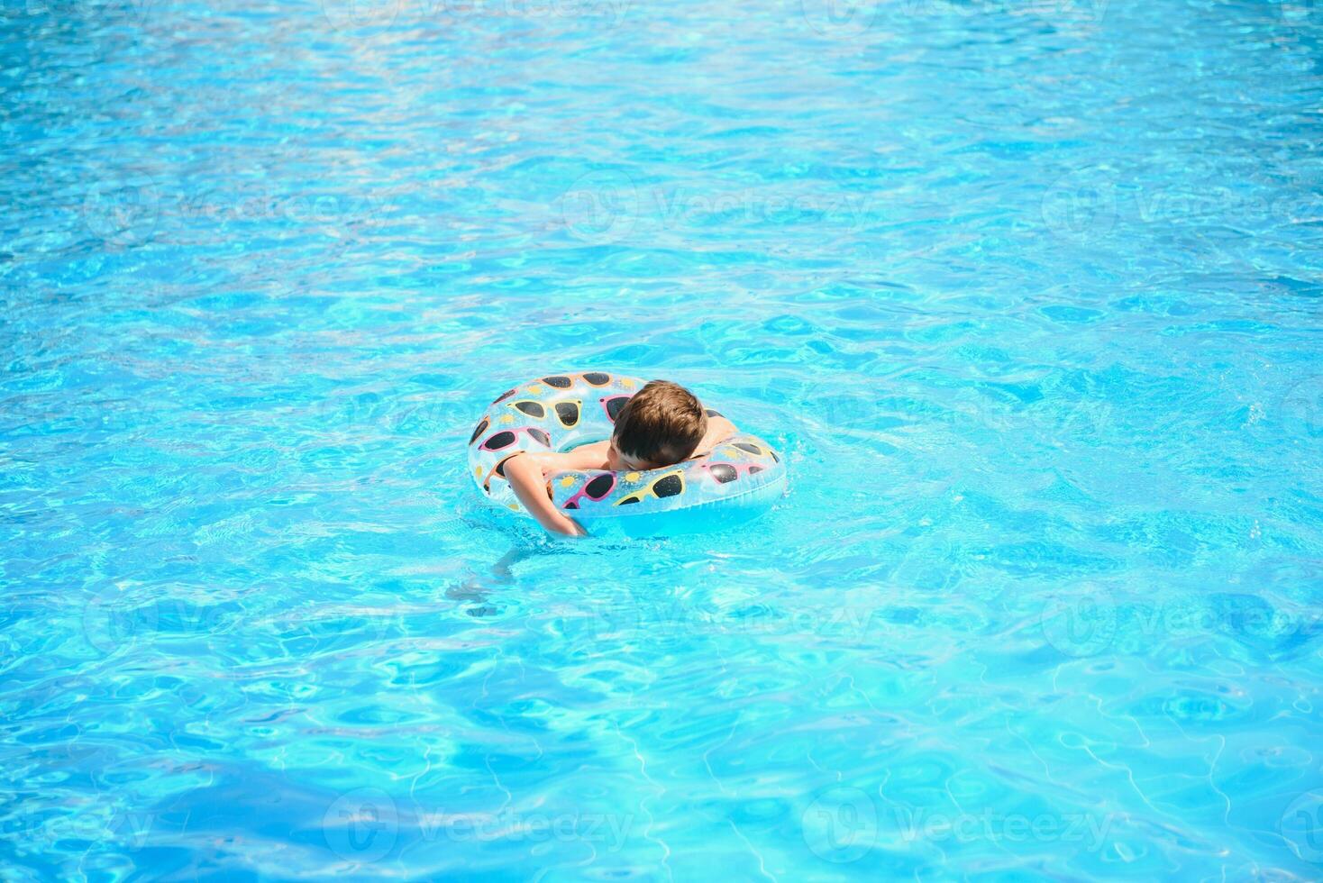 Happy Young Boy Floating in Swimming Pool on Raft photo