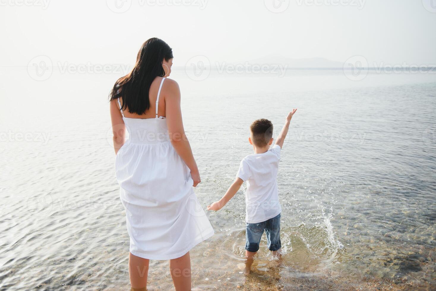 Happy mother and son walk along the ocean beach having great family time on vacation on Pandawa Beach, Bali. Paradise, travel, vacation concept photo