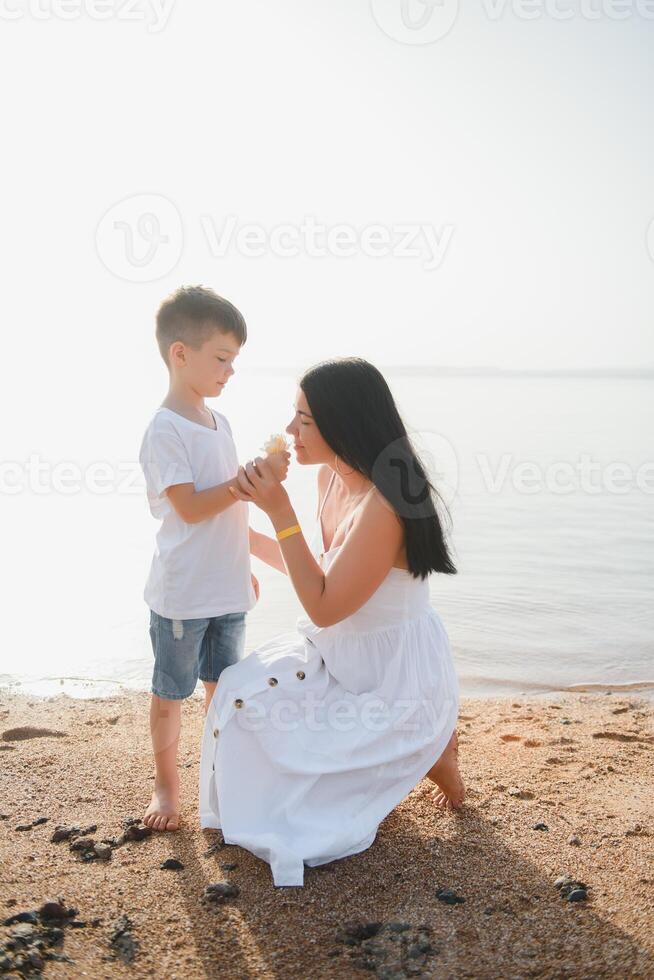 Mother and son playing on the beach at the day time. Concept of friendly family. photo
