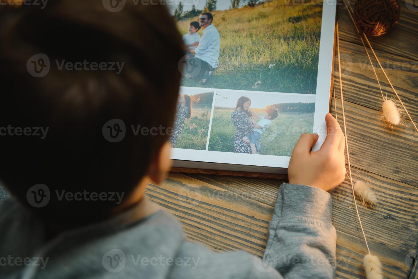 the Hand child holding a family photo album against the background of the a wooden table