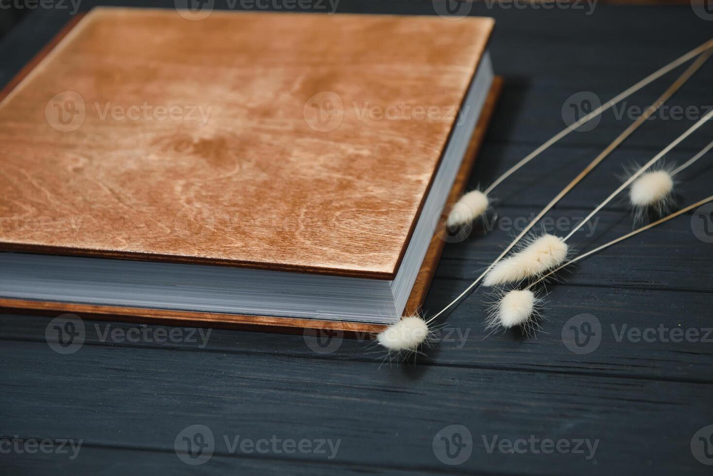 Family photo book with embossing. Photo book on a wooden background. Brown photo book with wood cover. Photoalbum with a hard cover. Wedding photo album.