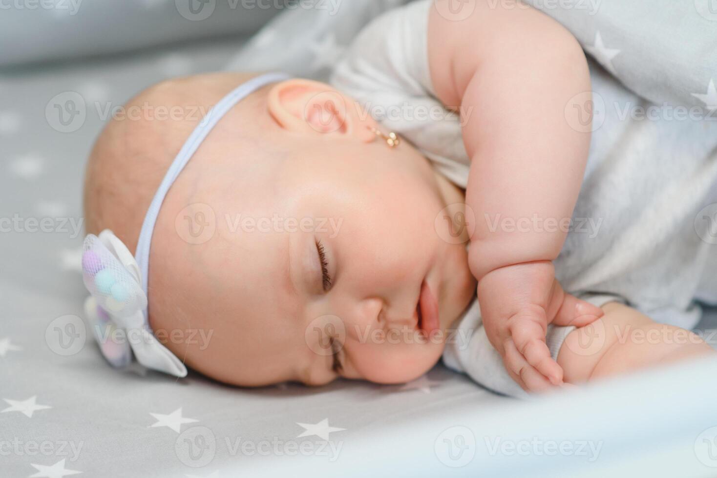 Adorable baby girl sleeping in the crib. Little child having a day nap in cot. Infant kid resting in nursery photo