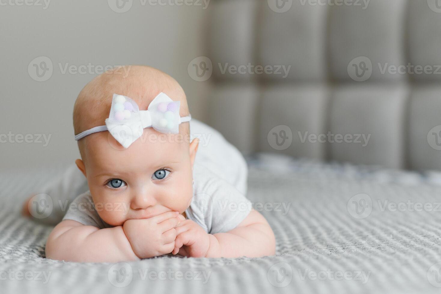 A Baby girl in white bedding at home look nice photo