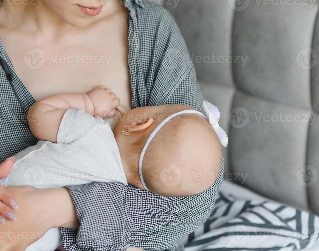 Young mother breastfeeding her newborn baby boy at home photo