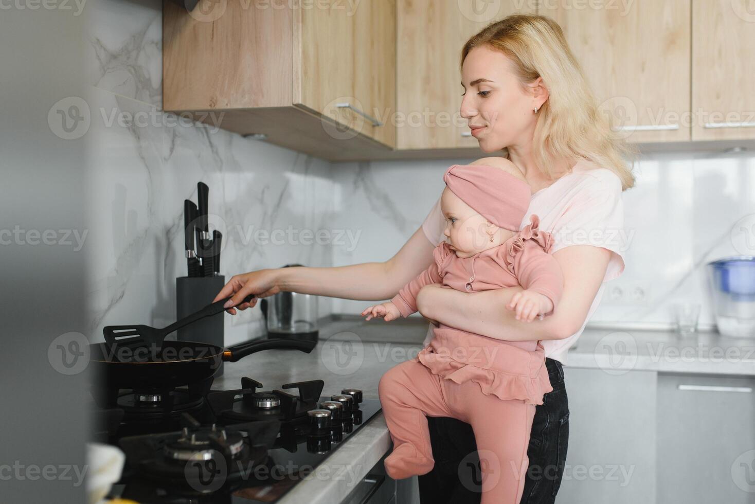 The mother of a woman with a baby cooks the food in a pot on the stove photo