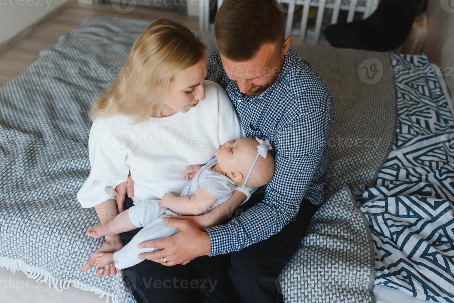 Happy relaxed couple sitting on sofa and looking at their baby photo