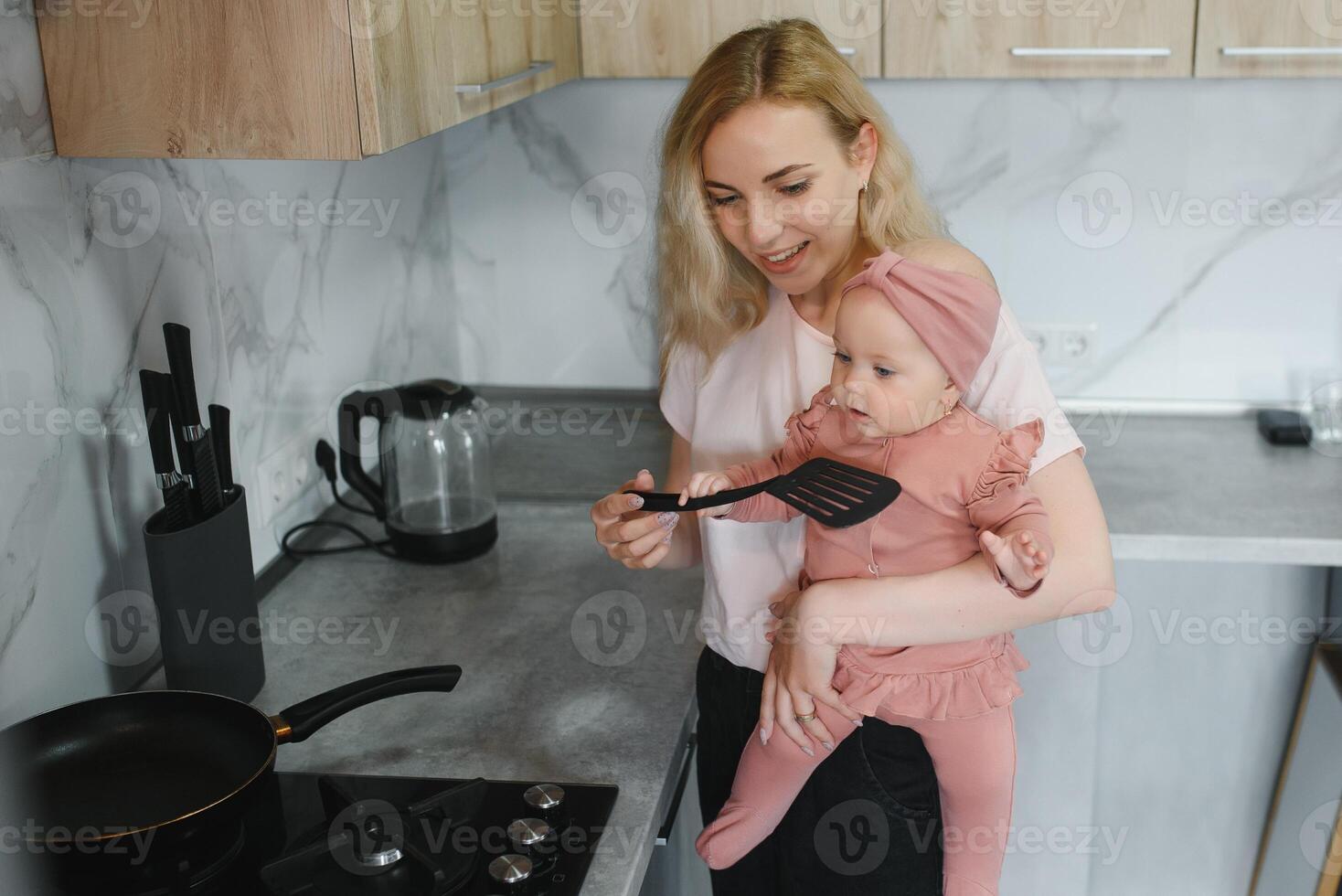 Woman cooking with her little daughter in hands photo