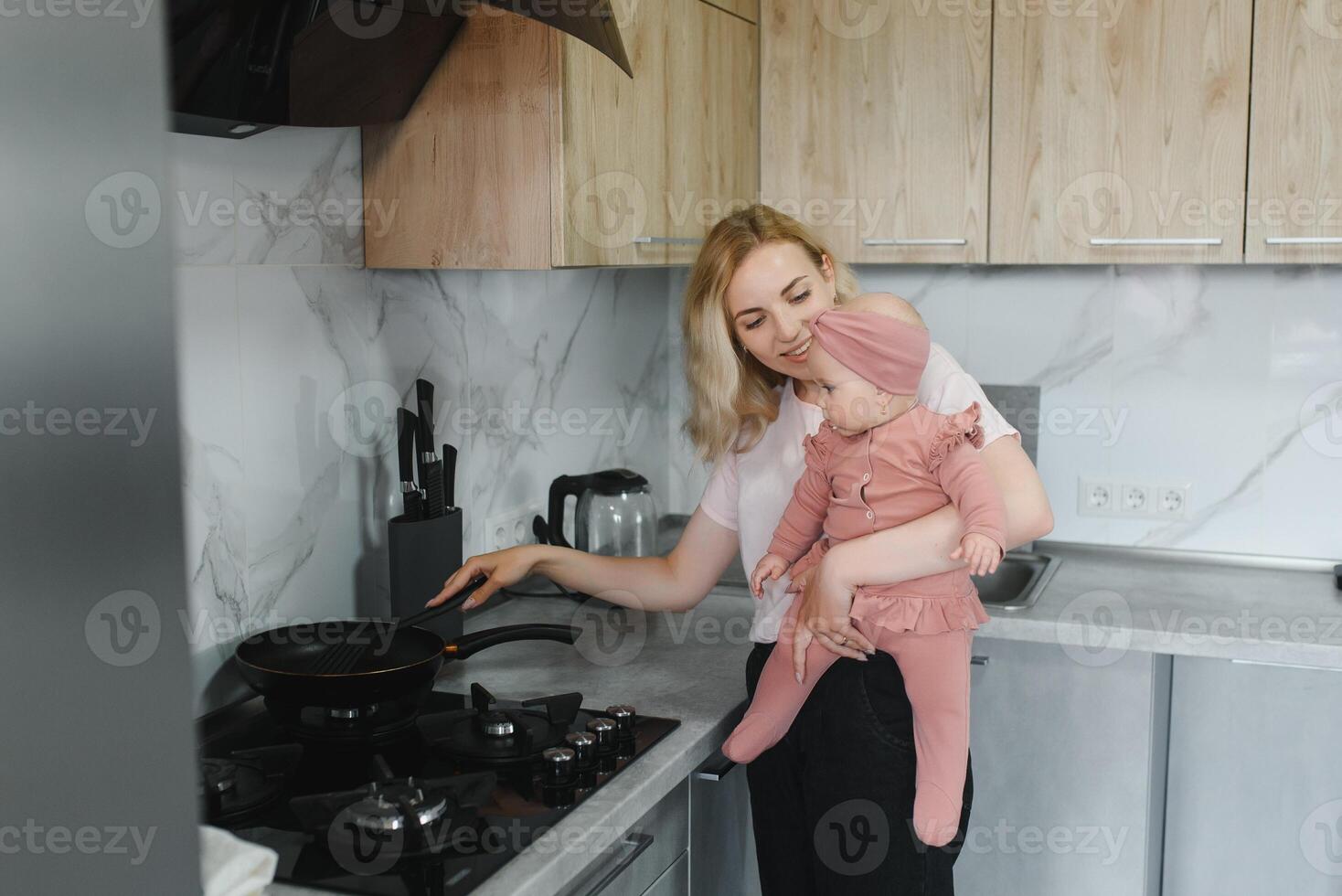 The mother of a woman with a baby cooks the food in a pot on the stove photo