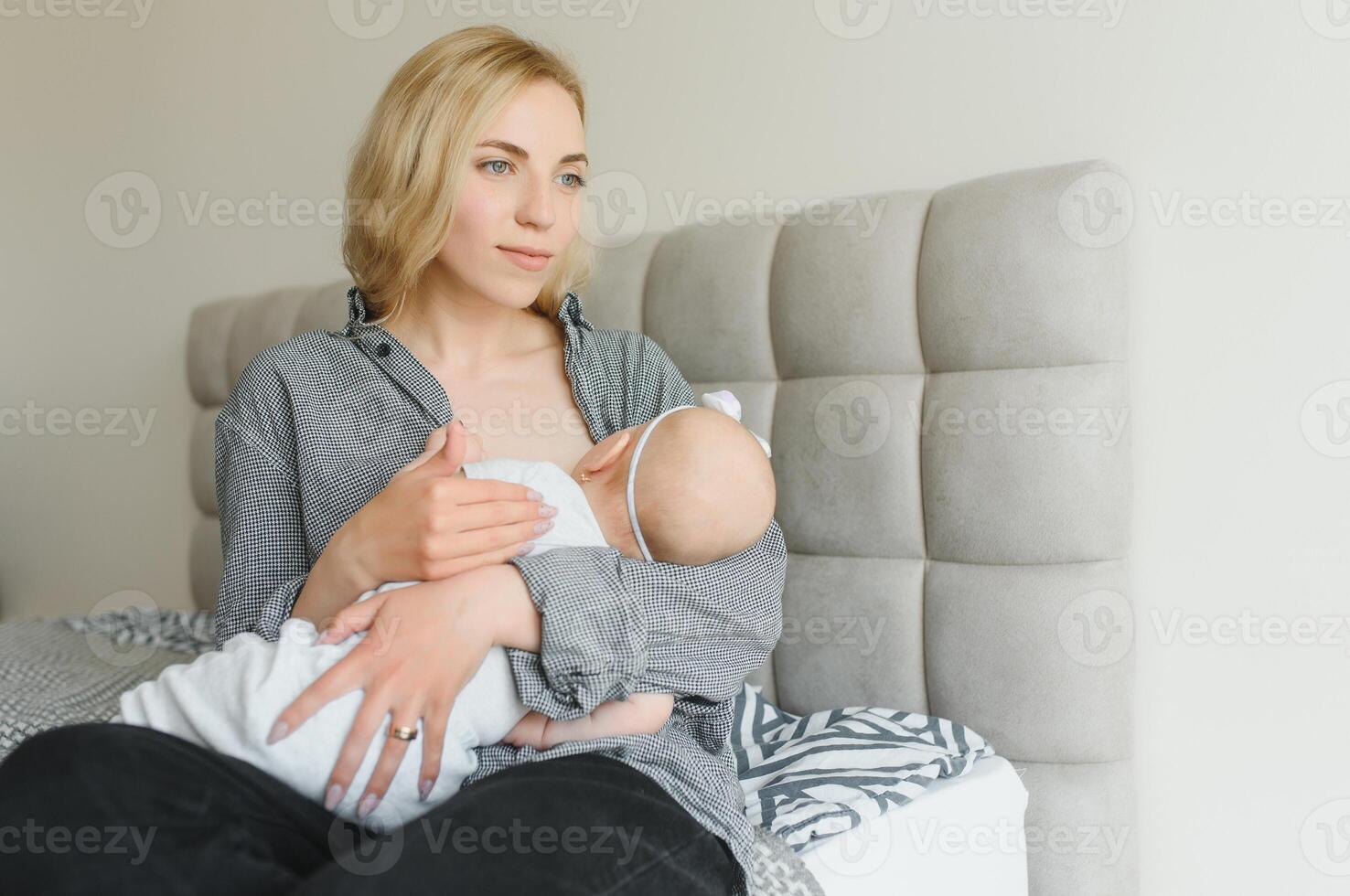 Young mother breastfeeding her newborn baby boy at home photo