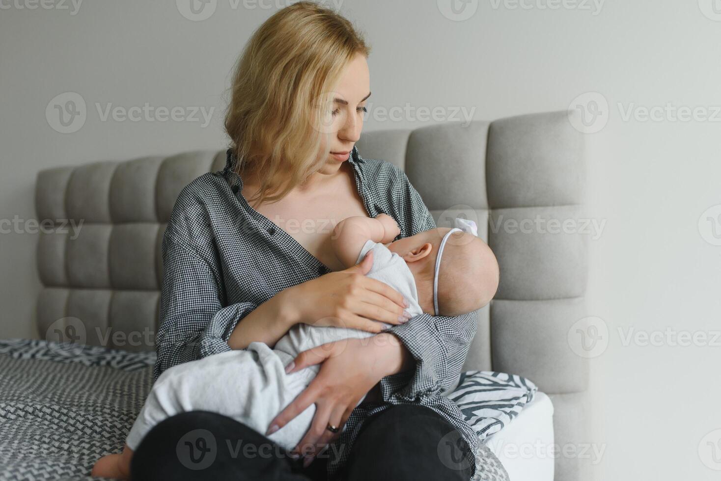 Young mother breastfeeding her newborn baby boy at home photo