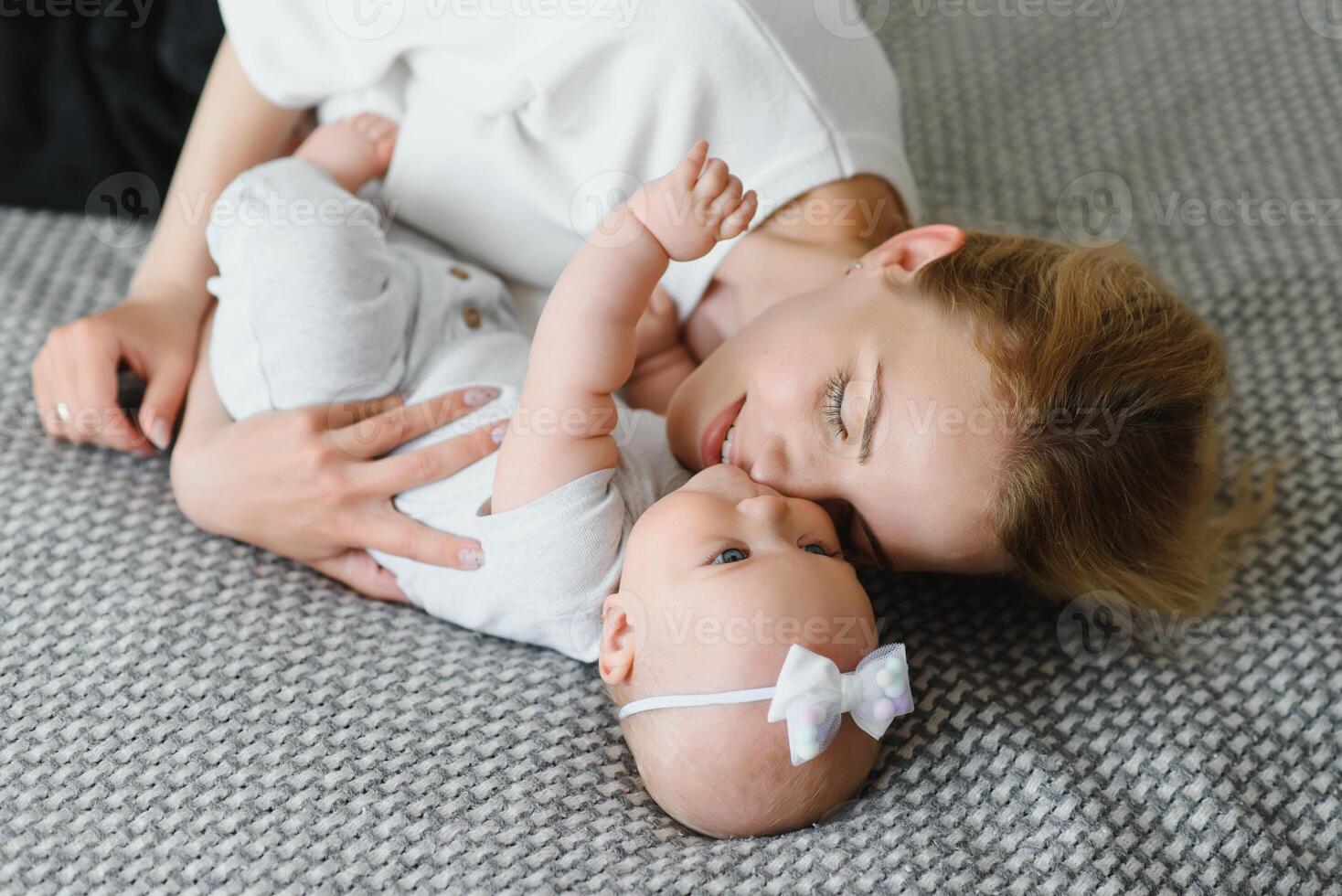 Happy smiling mother and baby lying on bed at home, top view photo