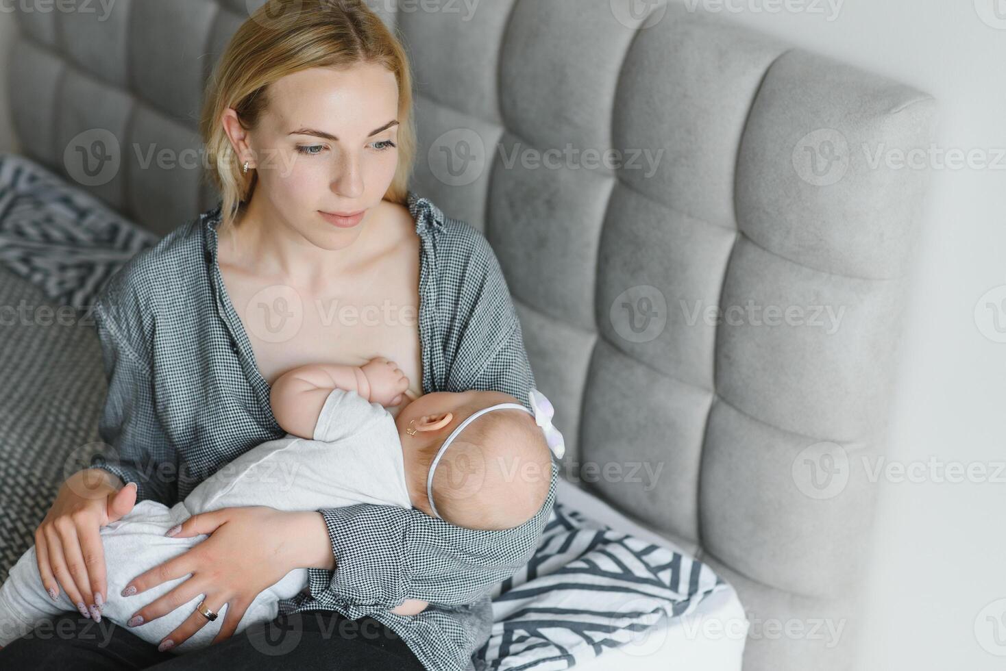 Breastfeeding Concept. Beautiful young woman lactating her toddler baby on couch at home, copy space photo