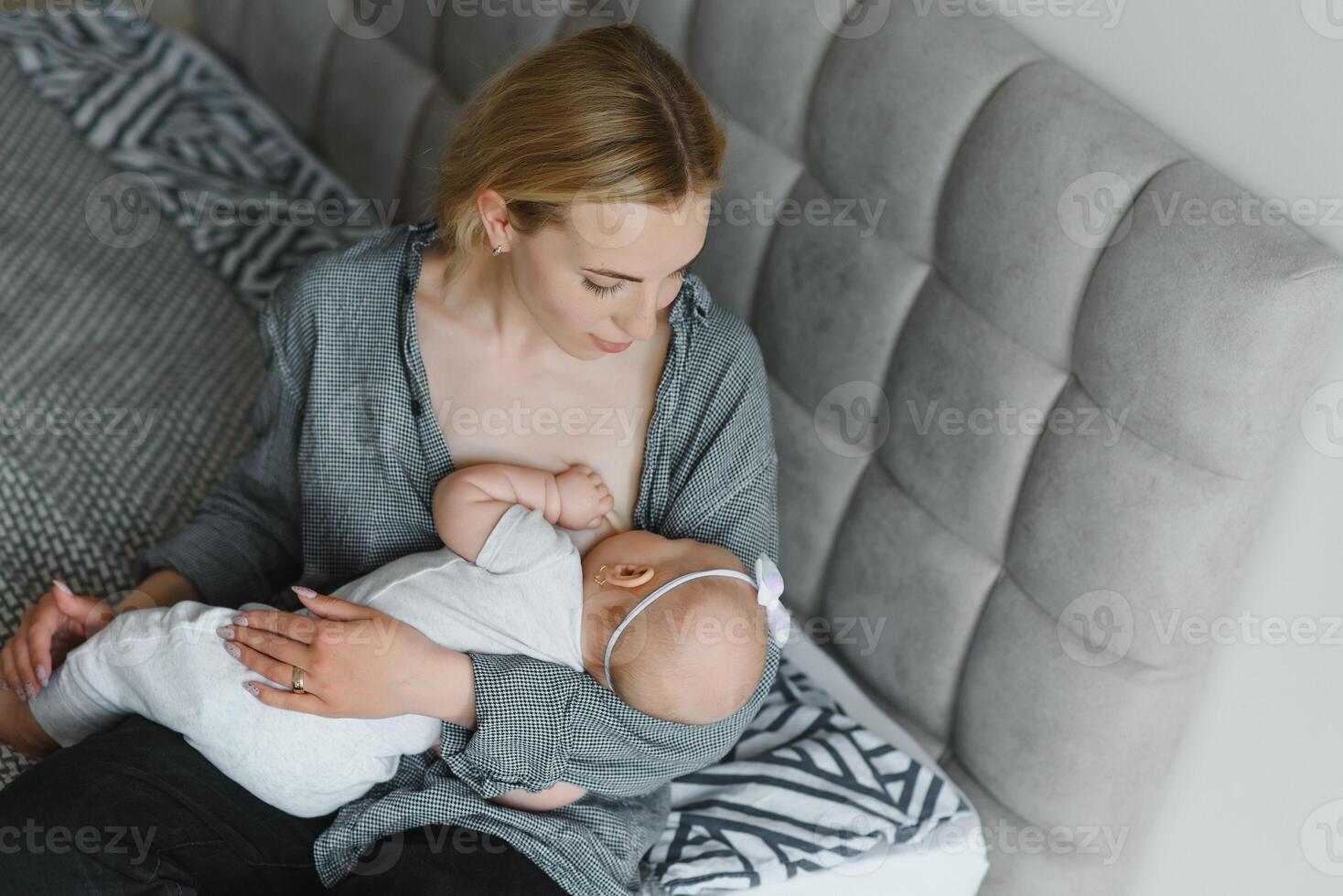 Lactation concept. Young mother breastfeeding her newborn baby at home, close up photo