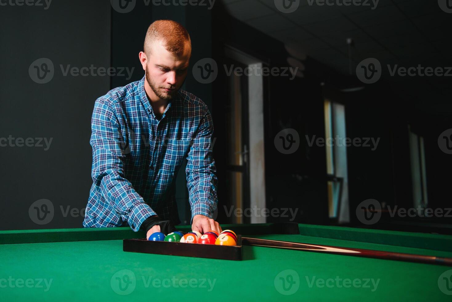 Young handsome man leaning over the table while playing snooker photo