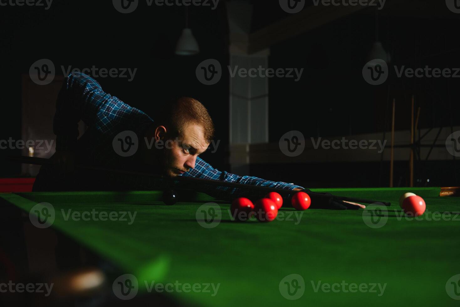 Young handsome man leaning over the table while playing snooker photo