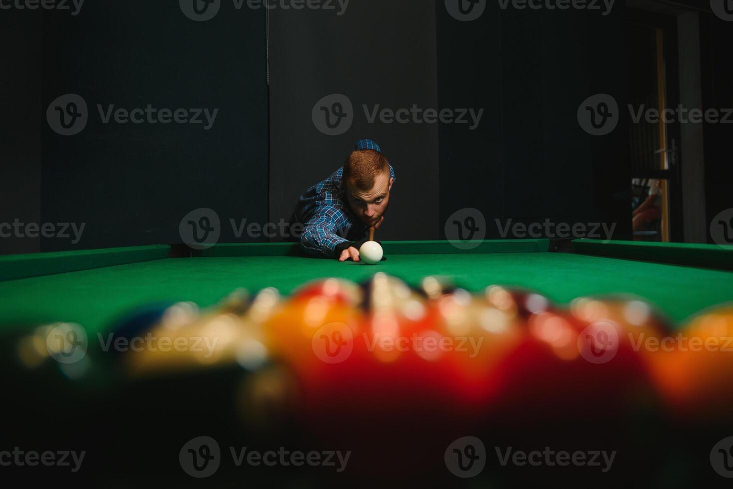 Young man playing billiards in the dark billiard club photo